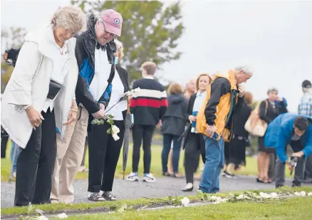  ?? JESSICA HILL PHOTOS/SPECIAL TO THE COURANT ?? Harry Fisher looks to place a flower on his brother Bennett Fisher’s granite stone at an annual 9/11 memorial ceremony Thursday at Sherwood Island State Park in Westport.