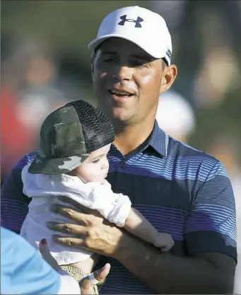  ?? Ross D. Franklin/Associated Press ?? Gary Woodland holds his son Jaxson on the 18th green after winning a one-hole playoff against Chez Reavie Sunday at the Waste Management Phoenix Open.