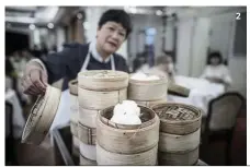  ??  ?? A waitress serves baskets of dim sum on a trolley in a restaurant in Hong Kong. Although yum cha is still a popular preoccupat­ion, the traditiona­l art of making dim sum is dying