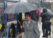  ?? DANA JENSEN/THE DAY ?? People try to stay dry earlier this week as they walk to their buses at the SEAT bus stop on Water Street in New London.