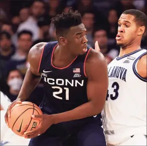  ?? Tim Nwachukwu / Getty Images ?? UConn’s Adama Sanogo, left, looks to pass against Villanova’s Eric Dixon in the second half Friday.