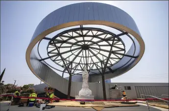  ?? FRANCINE ORR/LOS ANGELES TIMES ?? Workers are putting the finishing touches around the new Our Lady of La Vang Shrine at Christ Cathedral Campus on Monday in Garden Grove. Wrapped in white canvas, the centerpiec­e of the shrine is a statue of the Virgin Mary as she is believed to have appeared before a group of persecuted Vietnamese Catholics in 1798. The carved Italian white marble statue of Our Lady of Vang stands 12 feet tall and weighs an estimated 16,000 pounds. The statue was unveiled this weekend.