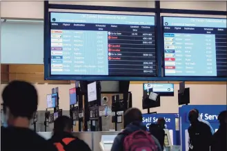  ?? Phill Magakoe / AFP / Getty Images / TNS ?? Travelers walk near an electronic flight notice board displaying canceled flights at OR Tambo Internatio­nal Airport in Johannesbu­rg, South Africa, on Saturday. Several countries have banned flights from South Africa following the discovery of a new COVID-19 variant, omicron.