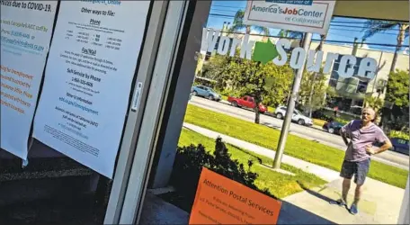  ?? Brian van der Brug Los Angeles Times ?? A MAN who didn’t want to be named is reflected in the window of a closed EDD office in Canoga Park last month. “I filed one month ago. Nothing has happened,” the man said. The agency reports a backlog of 1.12 million claims that have seen approval delayed by over 21 days.