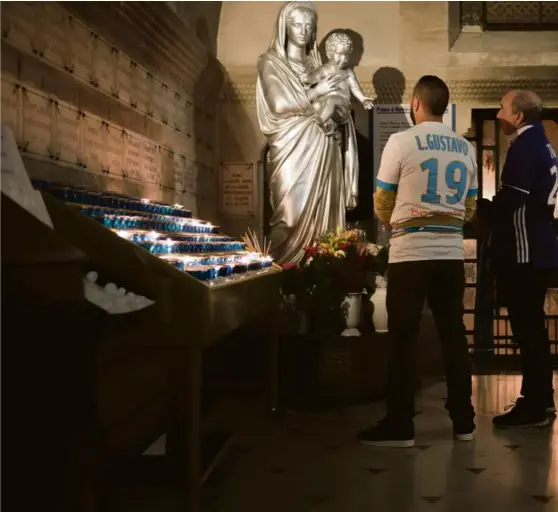  ?? PHOTO PATRICK GHERDOUSSI ?? Notre-Dame-de-la-Garde, mardi. William et Yannick, supporteur­s de l’OM, font brûler un cierge pour leur club.