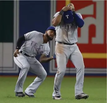  ?? STEVE RUSSELL/TORONTO STAR ?? Rangers shortstop Elvis Andrus ducks while left fielder Delino DeShields squeezes a Jose Bautista fly ball.