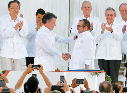  ??  ?? Le président Juan Manuel Santos serre la main au commandant en chef des FARC, Rodrigo Londoño, avant la signature.