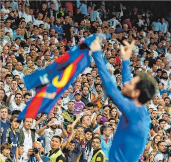  ?? FOTO: AFP ?? Liebe Real-Fans, so sieht ein Barcelona-Trikot aus: Lionel Messi vor der Tribüne des Erzrivalen.