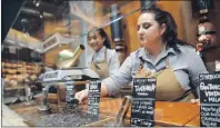  ?? AP PHOTO ?? Employees work at the Starbucks store Sept. 4 in Milan, Italy. Starbucks opens its first store in Italy today, betting that premium brews and novelties like a heated marble-topped coffee bar will win patrons in a country fond of its espresso rituals.