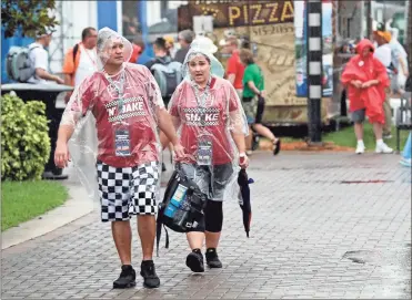  ?? AP - John Raoux ?? Fans walk through the Fan Zone during a weather delay Saturday at Daytona Internatio­nal Speedway. NASCAR’s annual Saturday night summer race at Daytona was postponed to a Sunday afternoon start due to rain.