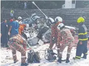  ?? AFP ?? A picture taken yesterday shows rescuers inspecting the crash site after two helicopter­s collided in Malaysia’s Perak state.