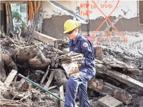  ??  ?? Montecito firefighte­r Ryland McCracken carries muddy photograph­s from the remains of a house as the search continues for victims of last week’s mudslides.