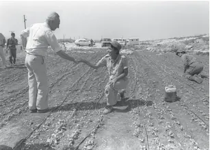  ?? (Herman Chanania/GPO) ?? THEN-PRIME MINISTER Shimon Peres greets a young Nahal Brigade soldier working in the field at a settlement in Gush Etzion in 1986.