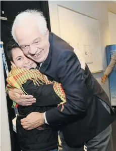  ??  ?? Federal Minister of Immigratio­n John McCallum hugs a Syrian boy. The message from such photos is that Canadians should pat themselves on the back for welcoming migrants to Canada, Douglas Todd writes.