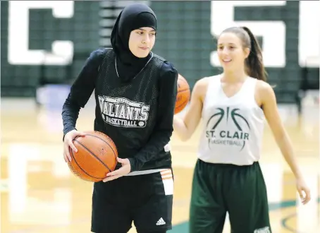  ?? PHOTOS: NICK BRANCACCIO ?? Saints freshman Noor Bazzi, left, practises with teammate Anna Ulicny at the St. Clair College SportsPlex on Wednesday. Bazzi, a shooting guard, will be playing varsity basketball as the first player in Saints history to wear a hijab and to be almost fully covered on court.