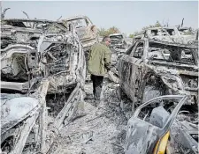  ?? OHAD ZWIGENBERG THE ASSOCIATED PRESS ?? A Palestinia­n man walks between scorched cars in a scrapyard, in the town of Hawara, near the West Bank city of Nablus on Monday.