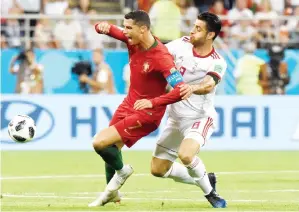  ?? — Gambar AFP ?? RONALDO (kiri) diasak Pouraligan­ji ketika bersaing pada perlawanan di Mordovia Arena, Saransk Isnin lepas.