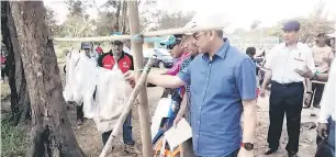  ??  ?? PERIKSA: Ripin memeriksa ikan yang berjaya dipancing sambil ditemani Julani (kanan).