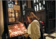  ?? KATHY WILLENS — THE ASSOCIATED PRESS ?? In this photo, a woman lights a candle at the entrance to All Saints Chapel inside Trinity Church in New York.