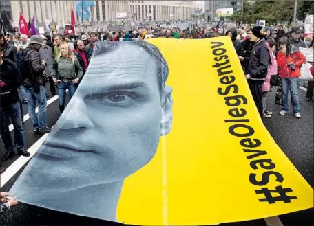  ?? Evgeny Feldman Associated Press ?? PROTESTERS CARRY a banner depicting political prisoner Oleg Sentsov during an opposition rally in Moscow this month. Sentsov, who says he is innocent, is serving a 20-year prison term in Russia after being convicted of plotting terrorist attacks in his...