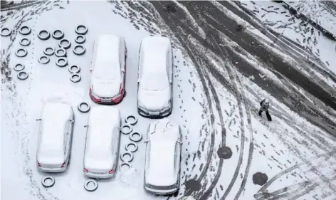  ?? — Reuters ?? A pedestrian passes by cars covered in snow, in Kyiv, Ukraine, on Wednesday.