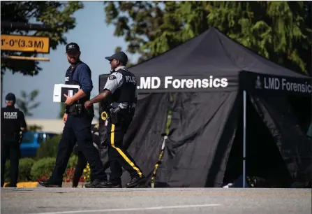  ?? The Canadian Press ?? RCMP officers talk as a tent covers a body at the scene of a shooting in Langley on Monday. A suspect is in custody after several people were shot in the Metro Vancouver city, RCMP said. Police issued a blaring cellphone alert at about 6:20 a.m., saying they were at the scenes of several shootings “involving transient victims.”