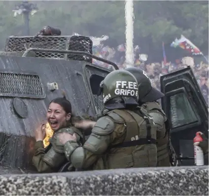  ?? AP ?? Una policía fue alcanzada por una bomba molotov durante enfrentami­entos con manifestan­tes.