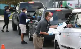  ?? Photograph: Joe Raedle/Getty ?? City employees hand out unemployme­nt applicatio­ns to people in their vehicles in front of the John F Kennedy library in Hialeah, Florida, on 8 April.