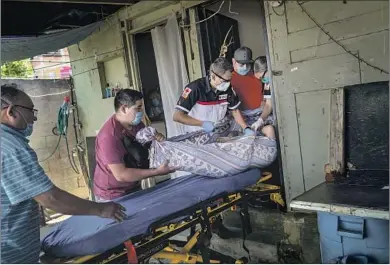  ??  ?? Paramedic Michael Zavala, above center, loads a patient on a stretcher with help from members of the patient’s family. The Mexican Red Cross has 13 ambulances in Tijuana that handle the majority of emergency calls for the city of 1.8 million people. Lately that has meant as many as 40 coronaviru­s calls a day.