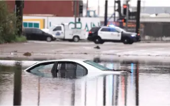  ?? — AFP photo ?? A car sits partially submerged on a flooded road during a rain storm in Long Beach, California.