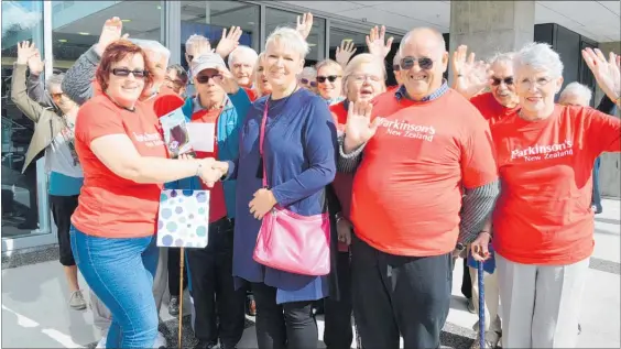  ??  ?? Surrounded by the Kapiti Parkinson’s community, Kitty Fitton, left, presents tulip bulbs to councillor Angela Buswell to mark World Parkinson’s Day.