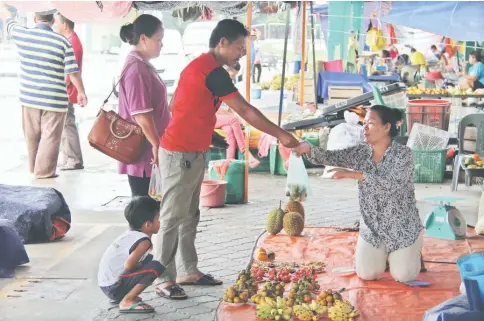  ??  ?? Michael and his family buying some limes from a woman vendor at the Lundu Wet Market.