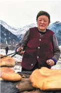  ??  ?? A housewife cooks naan bread near her