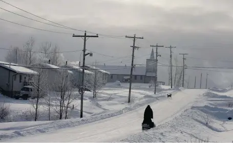  ?? RYAN REMIORZ/THE CANADIAN PRESS ?? A snowmobile rides down the main street on the Fort Hope First Nation, Ont., last winter. U.S.-based miner Cliffs Natural Resources Inc. says it will consider pulling out of the Ring of Fire project if the province doesn’t allow the company to build an...