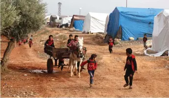  ?? — AFP photo ?? Displaced Syrian children run in front of a horse-drawn carriage at a camp for displaced Syrians near the town of Hazano in Idlib’s northern countrysid­e, after a night of heavy rainfall.