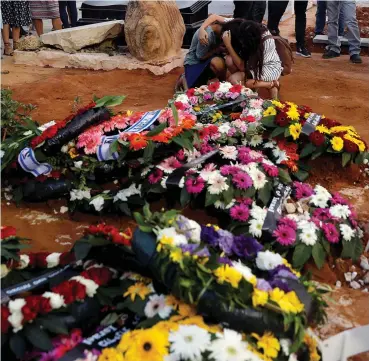  ??  ?? FAMILY AND FRIENDS mourn at the fresh graves of Yosef, Chaya and Elad Salomon, who were killed in a stabbing attack Friday night in Halamish (Neveh Tzuf), yesterday at Modi’in’s cemetery.