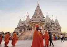  ?? Luis Andres Henao/Associated Press ?? Monks in saffron robes walk in front of the BAPS Swaminaray­an Akshardham, the largest Hindu temple outside India.
