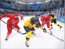  ?? AP PHOTO ?? Marcel Goc (57) of Germany battles for the puck between Russian athletes Vyacheslav Voynov (26) and Pavel Datsyuk (13) during the men’s gold-medal hockey game.