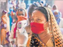  ?? AFP ?? An official checks the temperatur­e of a voter waiting to cast her ballot in Patna on Wednesday.