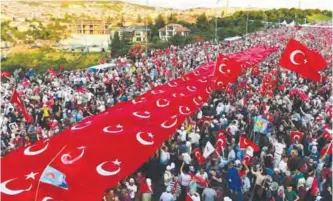  ??  ?? ISTANBUL: People stand under a collection of Turkish national flags as they gather on the ‘July 15 Martyrs Bridge’ (Bosphorus Bridge) in Istanbul. —AFP