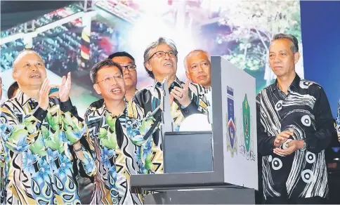  ?? Photo by Chimon Upon ?? Abang Johari (third right) with (from left) Chan, Dr Sim, Abang Abdul Wahap, Penguang and other guests look up at the fireworks display after performing the launch gimmick. –