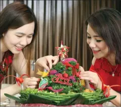  ?? DITE SURENDRA/JAWA POS ?? JAMUAN KELUARGA: Felicia Noviani (kiri) dan Fera Carolin Wijaya menyiapkan pohon Natal berbahan nasi lengkap dengan lauknya.