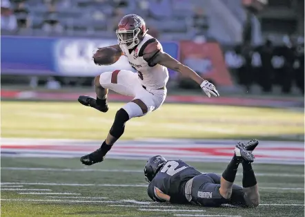  ?? PHOTOS BY RICK SCUTERI/THE ASSOCIATED PRESS ?? New Mexico State running back Larry Rose III leaps over Utah State safety Dallin Leavitt in the first half of the Arizona Bowl on Friday in Tucson, Ariz. New Mexico State won, 26-20, in its first bowl appearance in 57 years.