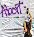  ?? ?? A woman paints a graffitti during a demonstrat­ion demanding the decriminal­isation of abortion. (AFP)