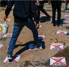  ?? ASSOCIATED PRESS ?? Anti-coup protesters walk on a road with defaced images of the military commander in chief in Yangon, Myanmar on Thursday. Videos showed a brutal crackdown against such protests continue.