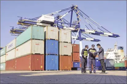  ?? ?? Custom officials check documents with a man at a container port in Yantai in eastern China’s Shandong province Tuesday, Oct 12, 2021. China’s import and export growth slowed in September amid shipping bottleneck­s and other disruption­s combined with coronaviru­s outbreaks. (AP)