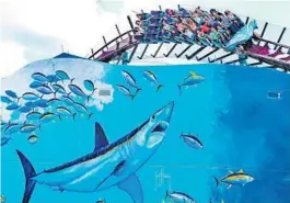  ?? RED HUBER/ORLANDO SENTINEL ?? Guests ride the Mako roller coaster behind a Guy Harvey mural.