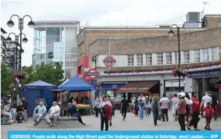  ?? ?? UXBRIDGE: People walk along the High Street past the Undergroun­d station in Uxbridge, west London.— AFP