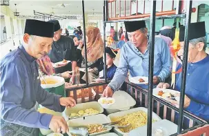  ??  ?? MESRA: Abang Mohamad (kiri) menjamu hadirin yang hadir pada majlis Ramah-Tamah Aidilfitri di Masjid Al-Muhajirin Kampung Usaha Jaya, Sentosa Salim, baru-baru ini.