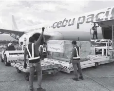  ?? Photo Courtesy of CEB ?? Airport terminal cargo handlers cautiously load a shipment of vaccines to a flight-bound Cebu pacific commercial airplane on Friday.